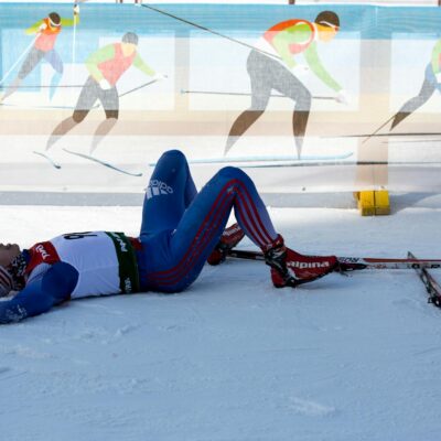 Cross-country skier lying on snowy ground after an intense race in Russia.