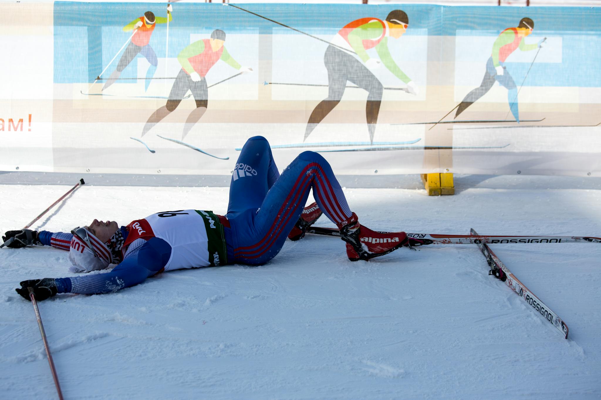 Cross-country skier lying on snowy ground after an intense race in Russia.