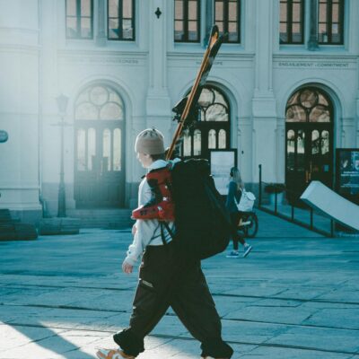 Man with skis walking through Oslo urban area on a sunny winter day.